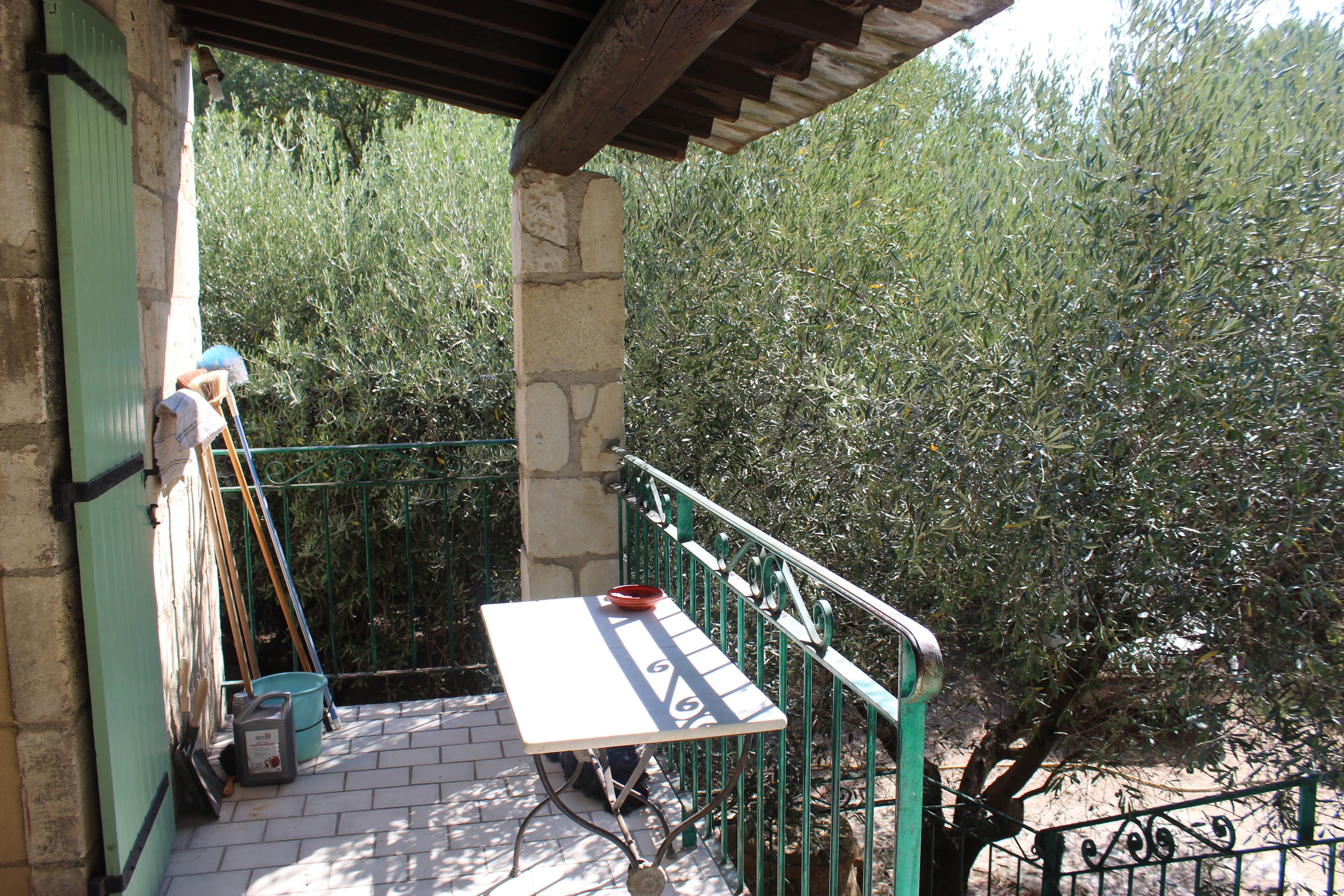 A balcony with a table, a bucket, and cleaning supplies.