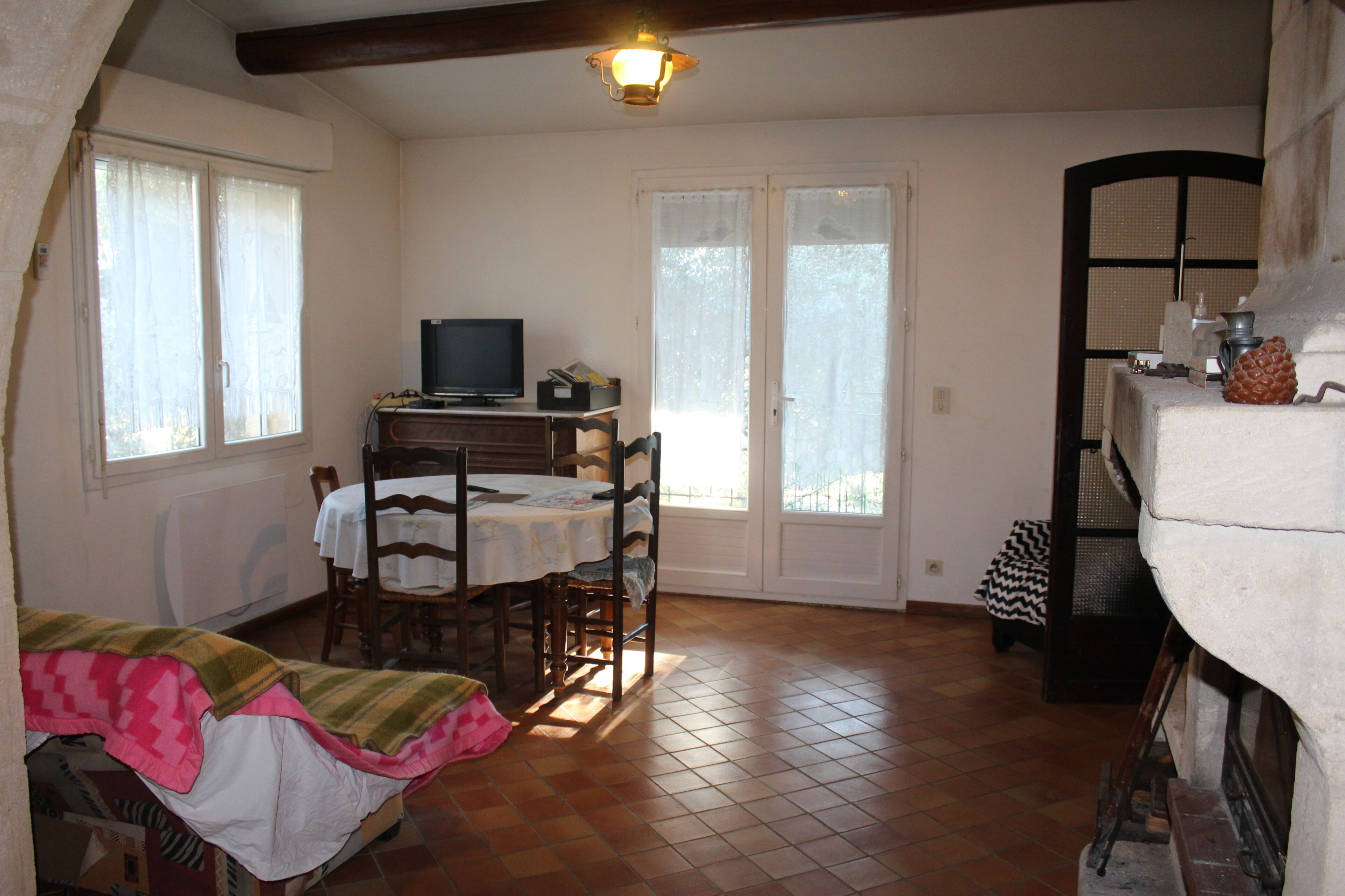 Ein gemütliches Zimmer mit einem Bett, einem Esstisch mit Stühlen, einem Fernseher und einem Kamin.