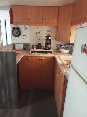 Une cuisine compacte avec des meubles en bois, une machine à café et une bouilloire posées sur le plan de travail.