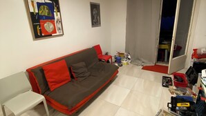 A living room with a sofa, a table, and a chair. There is a door leading to another room. - Renovated apartment, sea view, S-W orientation, terrace, near Monaco, Mala beach (Cap-d'Ail)