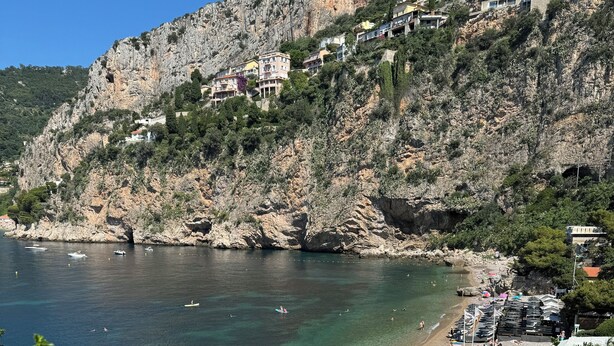 A coastal area with a rocky cliff, a beach with umbrellas, and boats in the water. - Renovated apartment, sea view, S-W orientation, terrace, near Monaco, Mala beach (Cap-d'Ail)