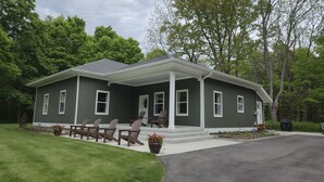 A two-story house with a covered porch, a lawn, and a driveway. - Newly Remodeled Cottage, 3 Bed, 2 Bath on 5 Acres--Walking distance to 2 Beaches (West Olive)