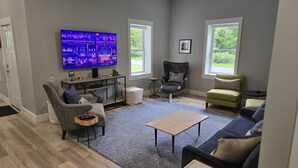 A living room with a flat-screen TV, two armchairs, a sofa, a coffee table, and a small side table. - Newly Remodeled Cottage, 3 Bed, 2 Bath on 5 Acres--Walking distance to 2 Beaches (West Olive)