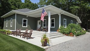 A two-story house with a porch, a flag, and outdoor seating. - Newly Remodeled Cottage, 3 Bed, 2 Bath on 5 Acres--Walking distance to 2 Beaches (West Olive)