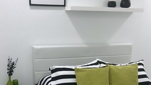 A bed with black and white striped bedding, a green pillow, and a bedside table with a vase and candles. - Seda Verde (Kissimmee)