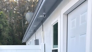 A covered patio area with two teal chairs, a white garage door, and a white fence. - Seda Verde (Kissimmee)