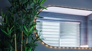 Ein Zimmer mit einem Holzkasten, einem Spiegel und einer Bambuspflanze in einem gewebten Korb.