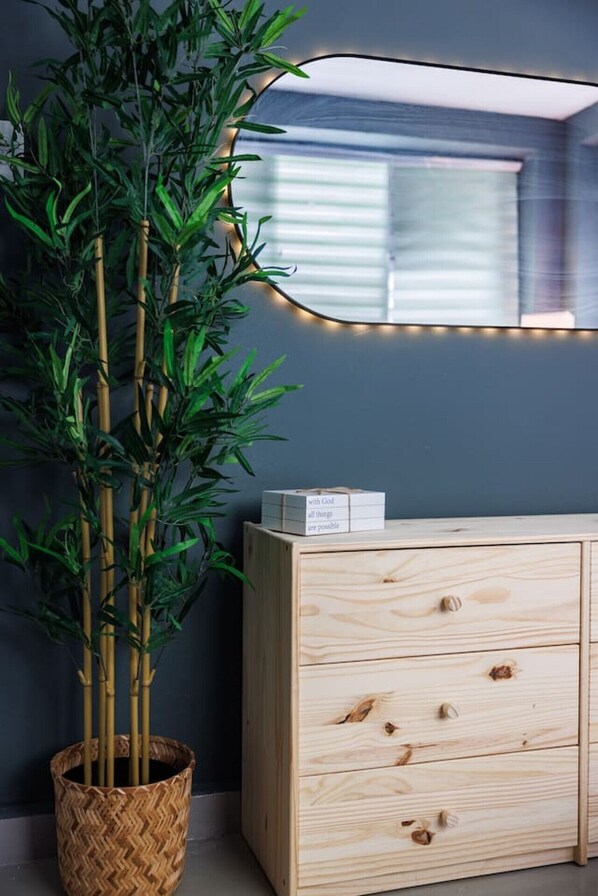 Een kamer met een houten kast, een spiegel en een bamboeplant in een gevlochten mand.