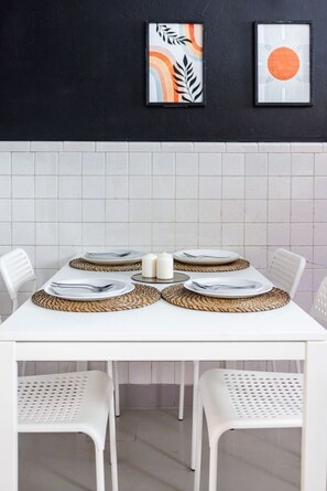 A dining table set with white plates, silverware, and woven placemats.