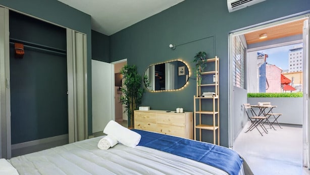 Ein Schlafzimmer mit Bett, Kommode, Spiegel und einem Balkon mit Tisch und Stühlen.