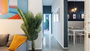 Ein modernes Interieur mit einer Couch, einer großen Pflanze, einem Essbereich und einer Küche.