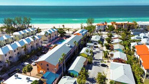 A resort with multiple buildings, a swimming pool, and a beach view.