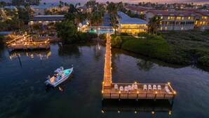 A waterfront resort with a dock, lounge chairs, and a pool.