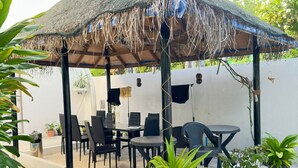 A covered outdoor seating area with tables and chairs, surrounded by potted plants. - AHI Maldives (Omadhoo)