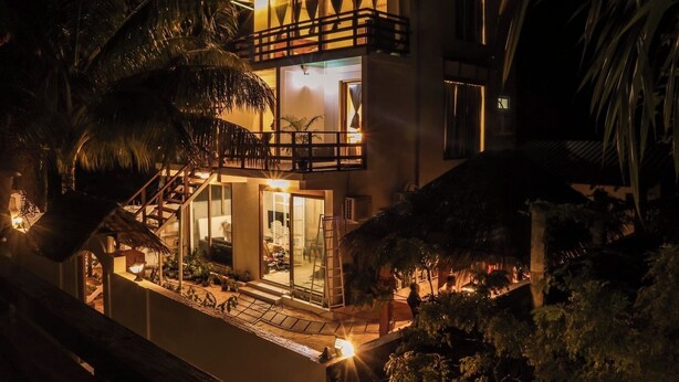 A two-story building with a balcony, a staircase, and a well-lit entrance. - AHI Maldives (Omadhoo)