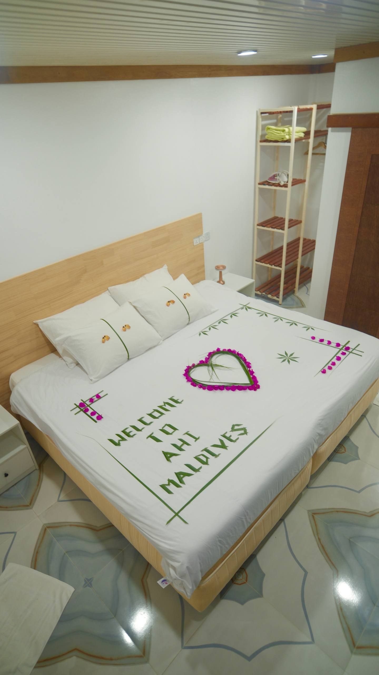 A neatly made bed with a welcome message, a wooden headboard, and a bedside table.