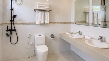 A modern bathroom with a toilet, bidet, and two sinks.