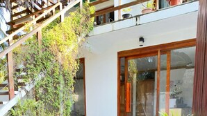 A modern outdoor patio with potted plants, a wooden staircase, and a glass door entrance. - AHI Maldives (Omadhoo)