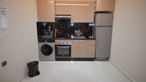Eine kleine Küche mit Waschmaschine, Backofen, Mikrowelle und Kühlschrank.