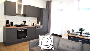 A modern kitchen with grey cabinets, a built-in oven, and a dining area with a table set for two. - Balcony in the center, Netflix & free coffee/tea (Chemnitz)