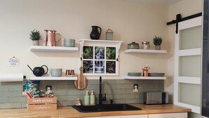 A modern kitchen with white cabinetry, a wooden countertop, and a built-in stove. There are shelves above the counter holding various kitchen items and a small window with a waterfall view. - BRAND NEW! 1-bedroom apartment in the beautiful historic village of Greene, NY (Greene)