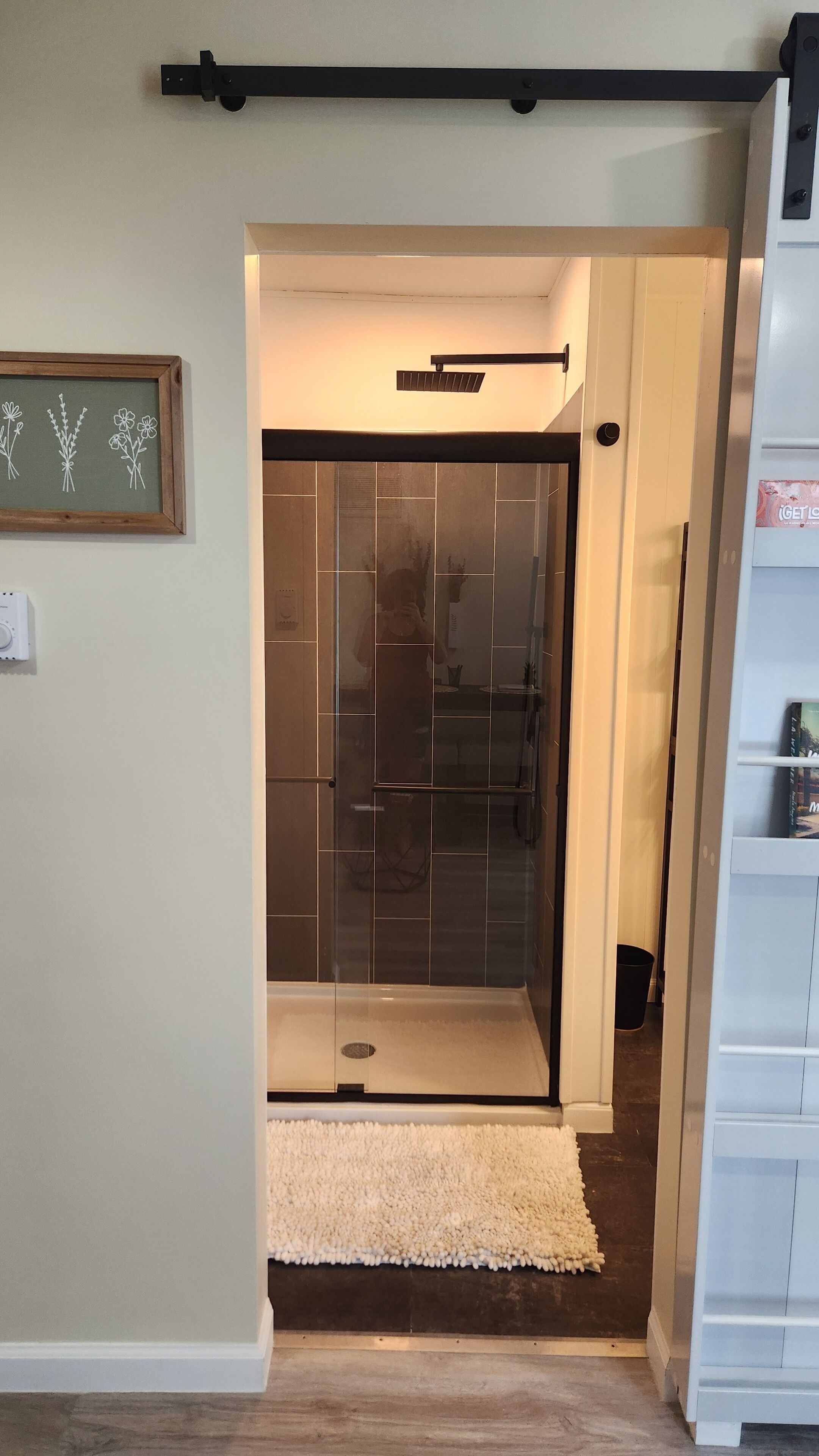 A modern bathroom with a glass shower enclosure, a white sink, and a towel rack.