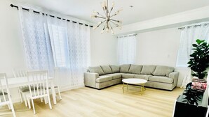 A modern living room with a sectional sofa, a dining table with chairs, and a small coffee table.