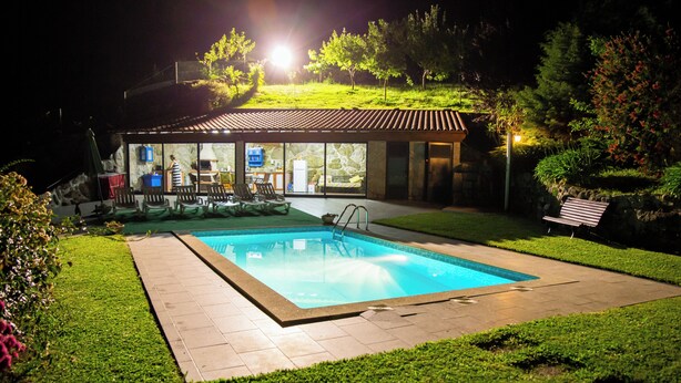 A modern house with a swimming pool, a covered patio, and a well-maintained garden.