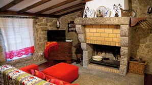 A cozy room with a stone fireplace, a television, and a red sofa.