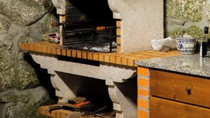 A stone wall with a built-in pizza oven, a wooden counter, and a drawer.
