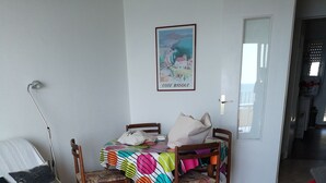 Una sala de estar con un sofá, una mesa de centro, una mesa de comedor con sillas y un cuadro en la pared.