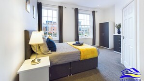 A modern bedroom with a bed, bedside table, lamp, and wardrobe. - 2br-sleeps4-citycentre-freeparking (Derby)