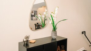 A mirror, a vase with flowers, and a small statue on a black console table. - Peaceful Pittsburgh Escape! Mins to North Shore, AGH, PNC Park, Rivers Casino! (Pittsburgh)