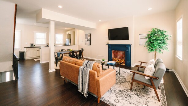 A spacious living room with a sofa, a chair, and a fireplace. There is a dining area with a table and chairs, and a kitchen in the background. - Peaceful Pittsburgh Escape! Mins to North Shore, AGH, PNC Park, Rivers Casino! (Pittsburgh)