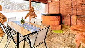 Un intérieur en bois comprenant une table à manger, des chaises, un jacuzzi et une statue.