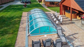 Une piscine couverte avec des chaises longues et un espace équipé d’un jacuzzi.