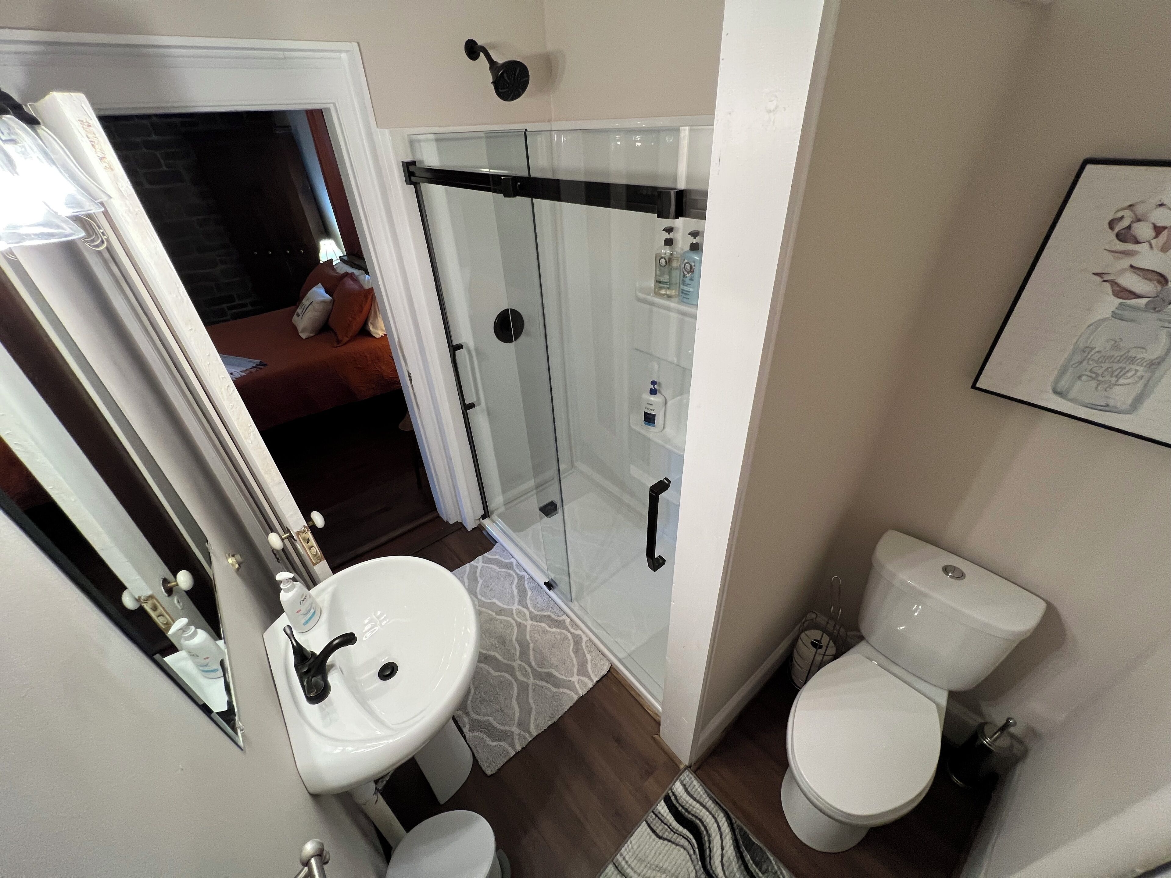 A bathroom with a white sink, toilet, and glass shower enclosure.