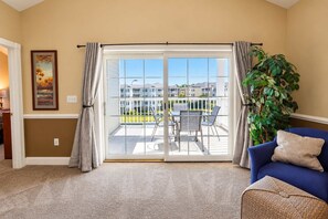 A living room with a sliding glass door leading to a balcony with outdoor furniture.