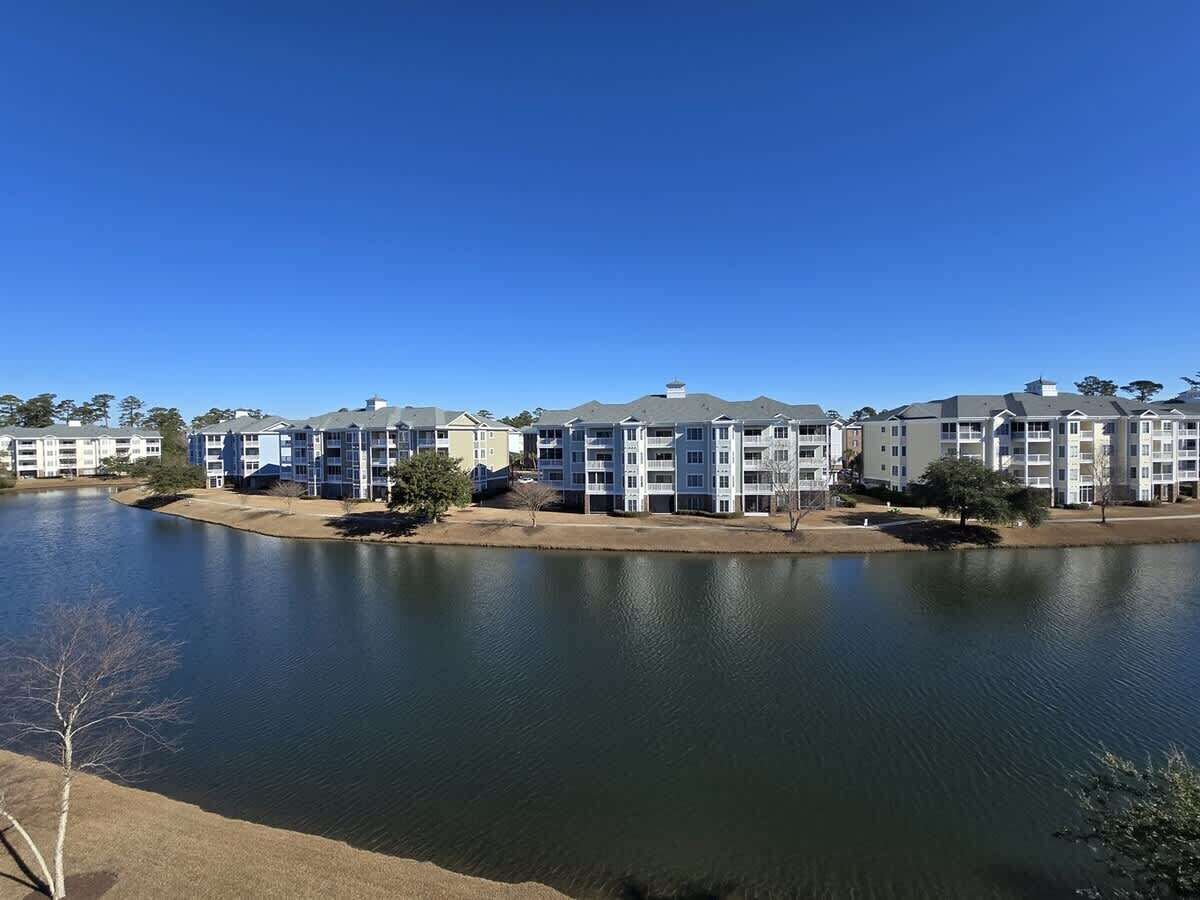 A row of multi-story residential buildings adjacent to a calm lake.