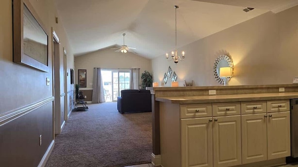 A spacious kitchen with a central island, a dining area with a dark sofa, and a view to the living room. - Myrtlewood Condo-Covered Porch, Pool & Hot Tub (Myrtle Beach)