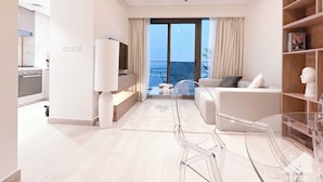 Ein modernes Wohnzimmer mit einer Couch, einem Glastisch und Meerblick durch große Fenster.