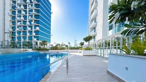 Ein modernes Hotel mit Schwimmbad, blauem Himmel und umliegender Bepflanzung.