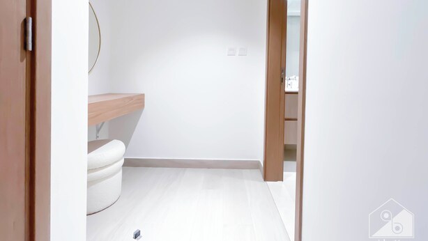 Ein schlichtes Badezimmer mit einer weißen Toilette, einem Holzwaschtisch und einem Spiegel.