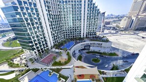 A modern high-rise building with a unique facade, a central courtyard with a pool, and a surrounding landscaped area. - Cozy 1BR With Balcony & Views in Azizi Fawad (Dubai)