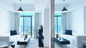 A modern hotel room with a large balcony, white furniture, and a view of the sea. - Cozy 1BR With Balcony & Views in Azizi Fawad (Dubai)