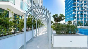 Un bâtiment moderne doté d’une passerelle couverte, d’espaces verts et d’une piscine.