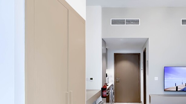 Une chambre d’hôtel moderne équipée d’un lit, d’une télévision, d’une armoire, d’un bureau et d’une salle de bain.