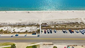 An aerial view of a beach with a parking lot and a road.