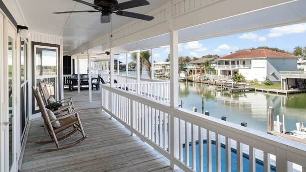 A covered porch with a view of a marina and houses. - Waterfront Home w/ Private Pool | Key Allegro | 5BR · Sleeps 14 (Rockport)