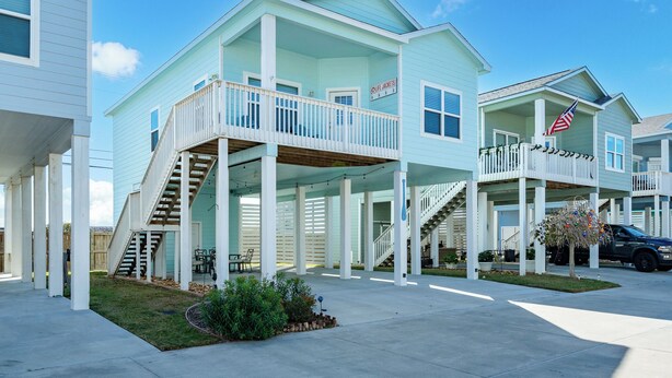 A coastal-style building with a balcony and a staircase leading to the upper level. - Coastal Getaway w/ Community Pool + Fishing Nearby (Rockport)